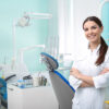 Young female dentist in white coat at workplace. Space for text